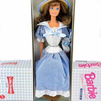 Barbie Little Debbie Series III (1997) è un’affascinante edizione da collezione lanciata da Mattel in collaborazione con il marchio Little Debbie. La bambola si distingue per la sua estetica dolce e vintage, ispirata alla classica immagine della “ragazza Little Debbie”, con <strong>abito blu a quadretti gingham</strong>, volant, maniche a sbuffo, colletto alla marinara e sottogonna integrata. Presentata nella sua scatola originale, è molto apprezzata dai collezionisti per il design nostalgico, l’edizione limitata e il legame con un marchio iconico della cultura pop statunitense.