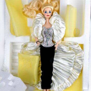 <strong>Barbie Crystal Rhapsody del 1992</strong>, prima bambola della prestigiosa <em>Presidential Porcelain Collection</em> di Mattel, è un’edizione limitata che si distingue per raffinatezza, materiali di lusso e design teatrale. La collezione fu pensata per rappresentare il massimo dell’arte nelle bambole in porcellana, destinata ai collezionisti adulti.

Barbie indossa un <strong>corpetto argentato decorato con 75 cristalli Swarovski austriaci</strong>, che donano una brillantezza elegante. La gonna è in <strong>velluto nero di seta</strong> e l’insieme è completato da un <strong>mantello bianco plissettato in satin crêpe</strong>. Include base espositiva, certificato di autenticità ed elementi originali da collezione.